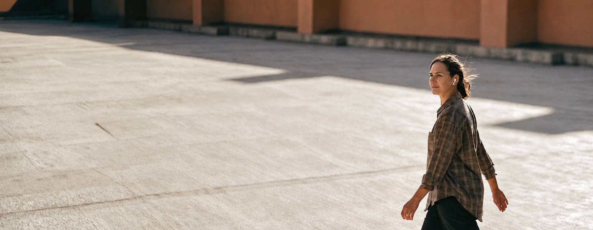 A person walking across a wide paved square on a bright day.