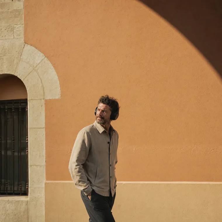 A person walking outdoors, listening through headphones.